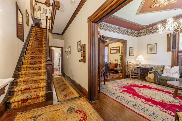 hall with hardwood / wood-style flooring, ornamental molding, and a chandelier