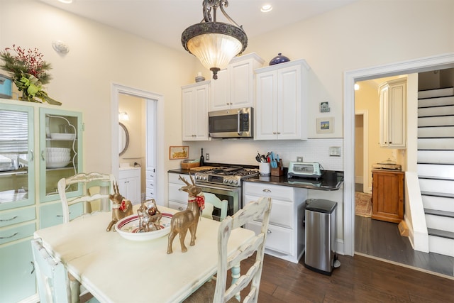 kitchen with pendant lighting, dark wood-type flooring, tasteful backsplash, white cabinetry, and stainless steel appliances