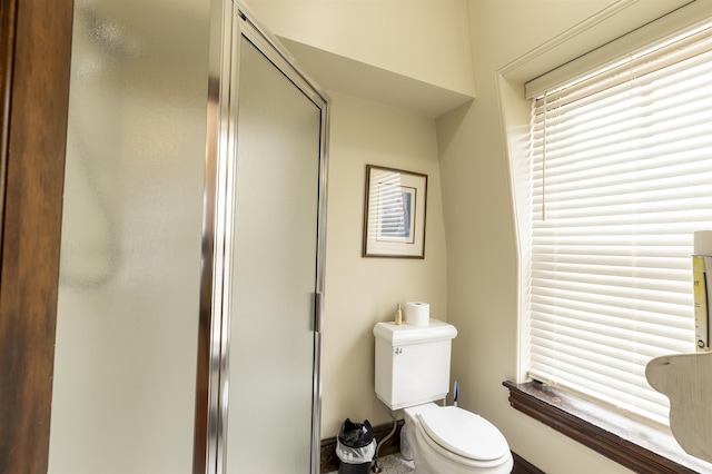 bathroom featuring a shower with shower door and toilet