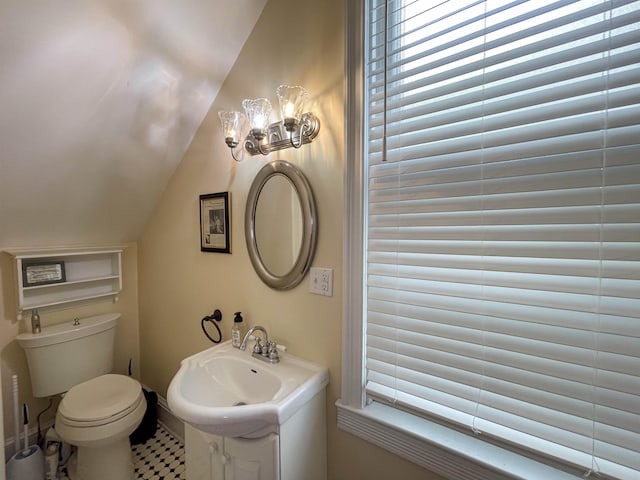bathroom with toilet, lofted ceiling, and sink