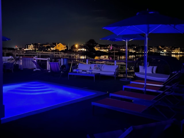 pool at twilight featuring a water view