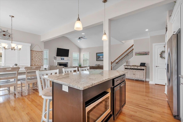 102 E 8 Th Ave, North Wildwood, NJ 08260 - kitchen featuring stainless steel appliances, light wood-style floors, ceiling fan, a kitchen bar, and a fireplace