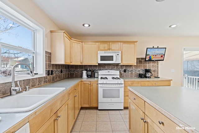 kitchen with light tile patterned flooring, light brown cabinetry, sink, white appliances, and backsplash