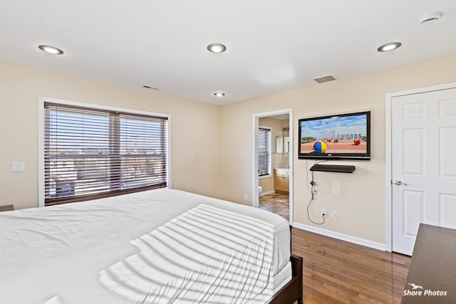 bedroom featuring ensuite bathroom and dark hardwood / wood-style flooring