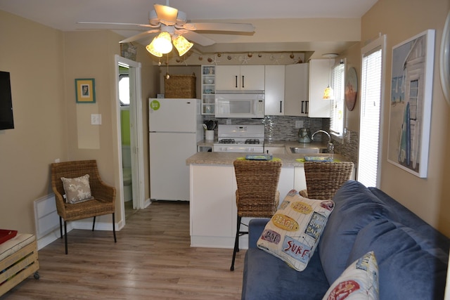 kitchen featuring white appliances, ceiling fan, sink, light hardwood / wood-style flooring, and white cabinets