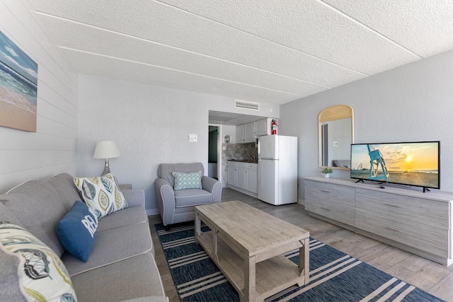 living area featuring light wood-style floors and a textured ceiling