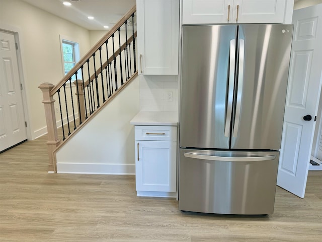 kitchen with tasteful backsplash, stainless steel refrigerator, light hardwood / wood-style flooring, and white cabinets