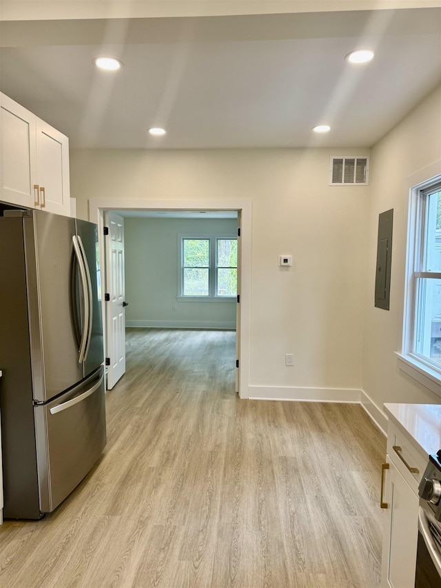 kitchen with electric panel, white cabinets, light hardwood / wood-style floors, and appliances with stainless steel finishes