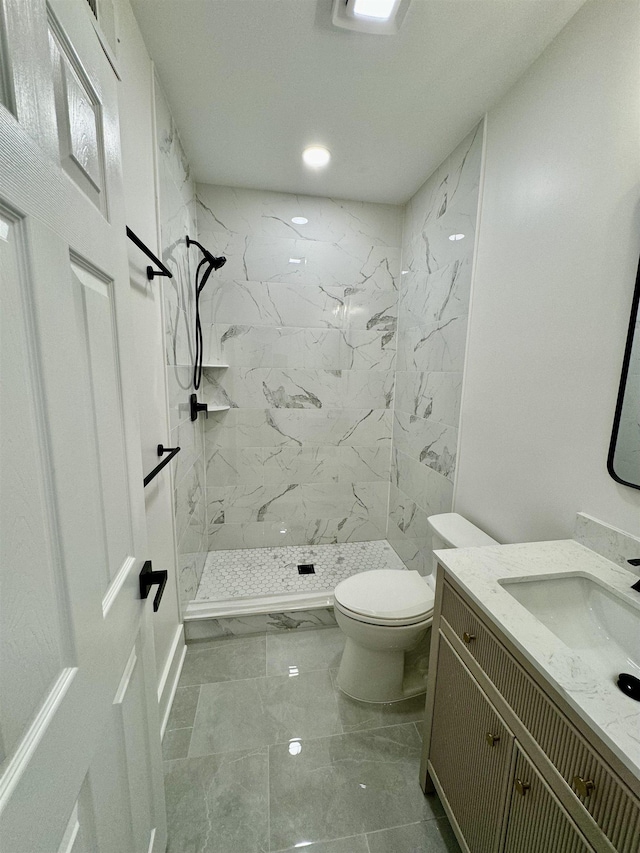 bathroom with vanity, toilet, and tiled shower