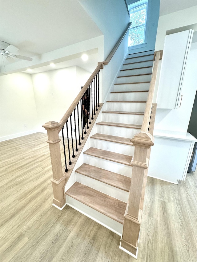 stairway with ceiling fan and wood-type flooring