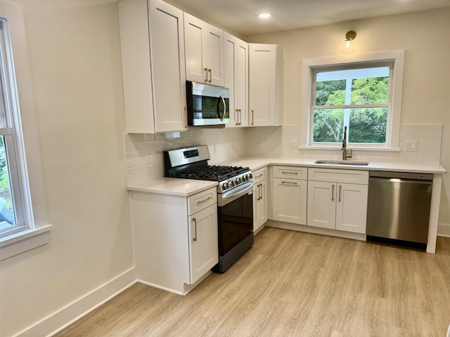 kitchen with white cabinets, sink, light wood-type flooring, and stainless steel appliances