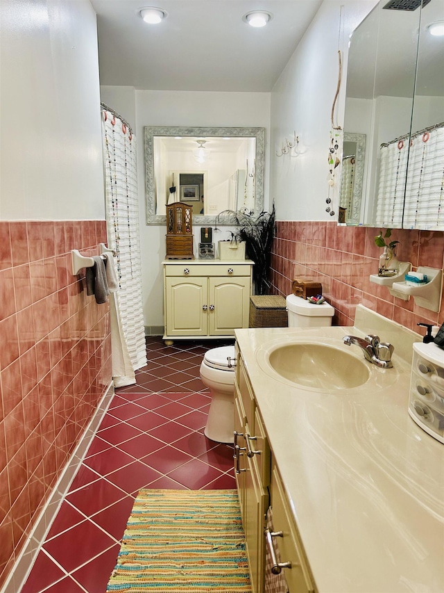 bathroom featuring toilet, vanity, tile patterned floors, and tile walls