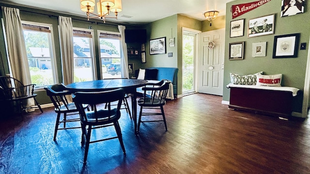 dining area with dark wood-type flooring, a healthy amount of sunlight, and a notable chandelier