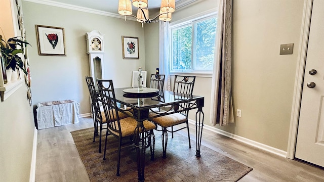 dining area featuring wood-type flooring, crown molding, and a notable chandelier