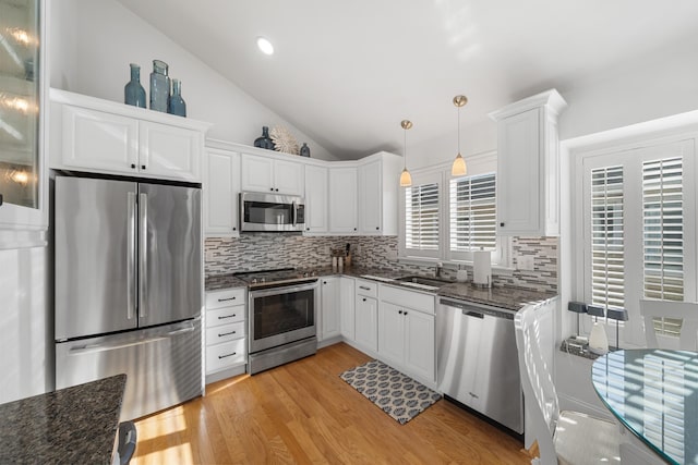 260 83rd St Unit 1, Stone Harbor, NJ 08247 - kitchen with appliances with stainless steel finishes, backsplash, vaulted ceiling, white cabinets, and light wood-type flooring