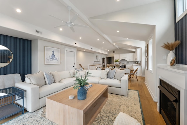 living room with ceiling fan, lofted ceiling with beams, and light hardwood / wood-style flooring