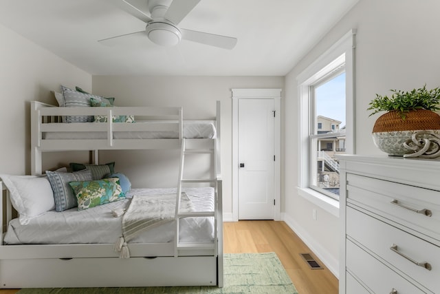 bedroom featuring ceiling fan, light hardwood / wood-style floors, and multiple windows