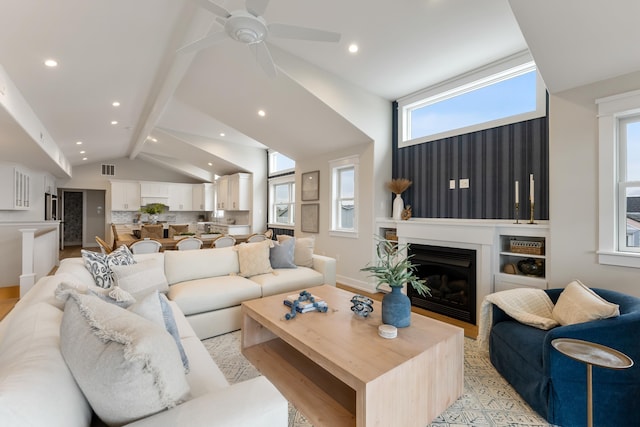 living room with ceiling fan and vaulted ceiling with beams