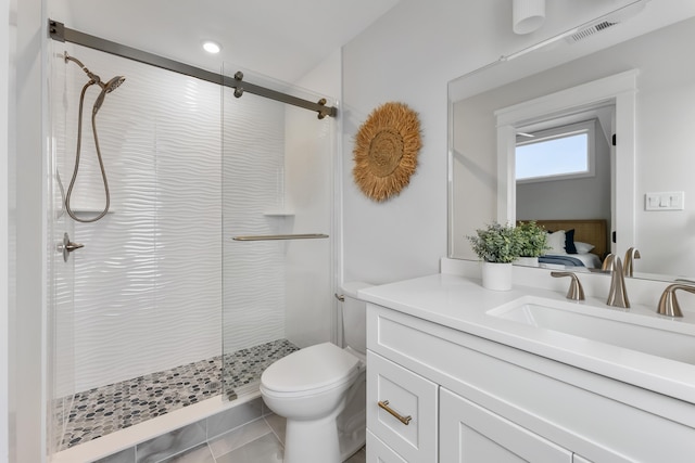 bathroom with a shower with door, vanity, tile patterned floors, and toilet