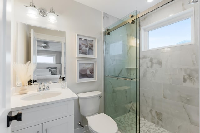 bathroom featuring toilet, ceiling fan, a shower with shower door, and a wealth of natural light