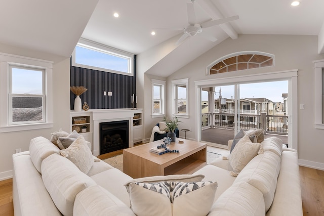 living room with ceiling fan, lofted ceiling with beams, a healthy amount of sunlight, and light hardwood / wood-style flooring