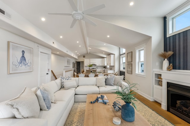 living room featuring ceiling fan, light wood-type flooring, and lofted ceiling