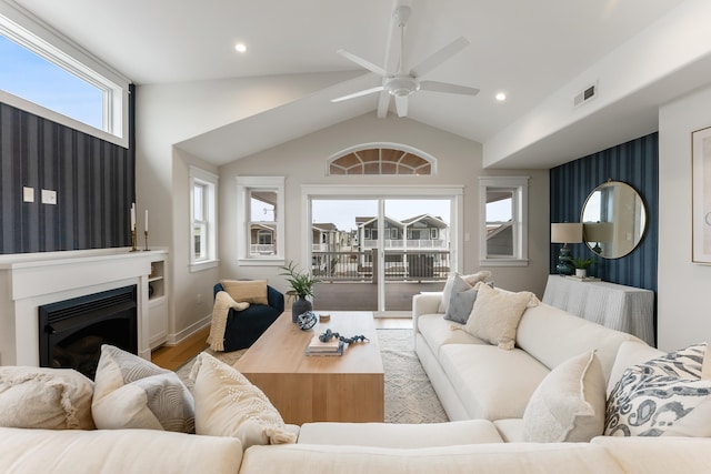 living room with ceiling fan, light wood-type flooring, and vaulted ceiling