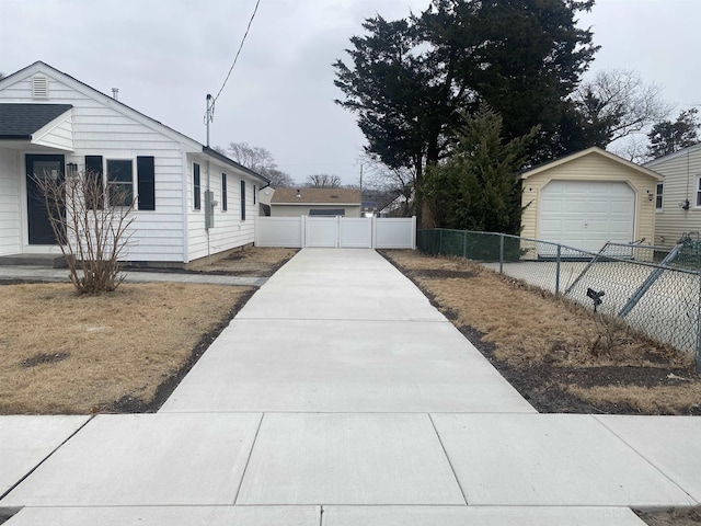 view of side of home with a garage, concrete driveway, an outdoor structure, and fence