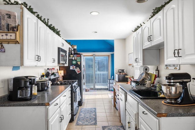 kitchen with dark countertops, white cabinets, appliances with stainless steel finishes, and a sink