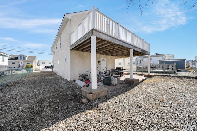 back of property with stucco siding, fence, a wooden deck, and a patio area
