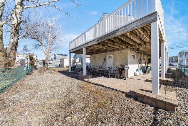 rear view of house featuring a patio area, stucco siding, a wooden deck, and fence