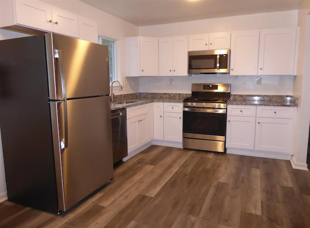 kitchen with dark wood finished floors, appliances with stainless steel finishes, a sink, and white cabinetry