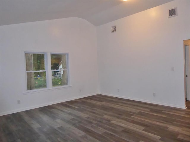 empty room with dark wood-style floors, lofted ceiling, visible vents, and baseboards