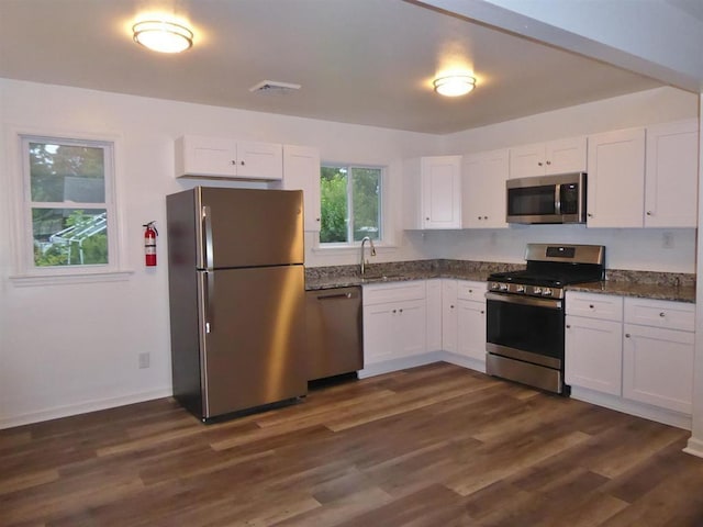 kitchen with white cabinets, dark wood-type flooring, stainless steel appliances, and a sink