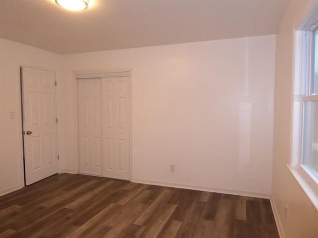 unfurnished room with dark wood-style flooring and baseboards