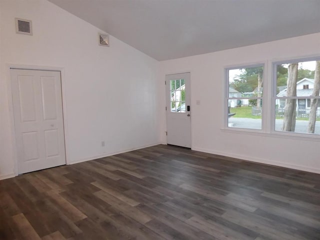 spare room featuring lofted ceiling, dark wood-style flooring, visible vents, and baseboards