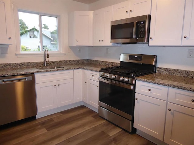 kitchen with stone counters, stainless steel appliances, dark wood-type flooring, a sink, and white cabinetry