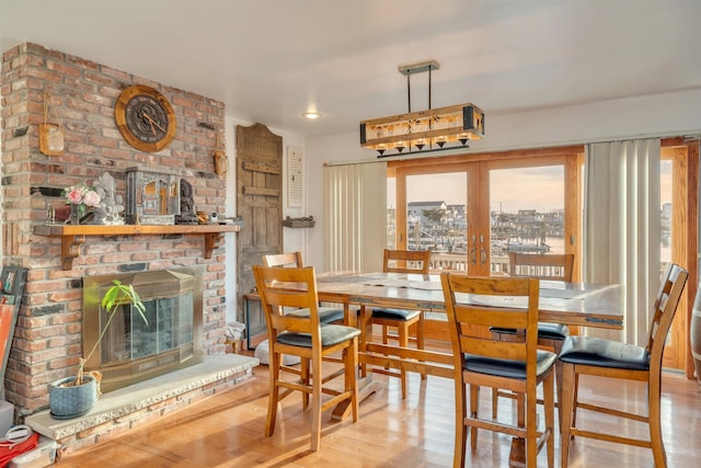 dining area featuring french doors, a brick fireplace, and light hardwood / wood-style flooring