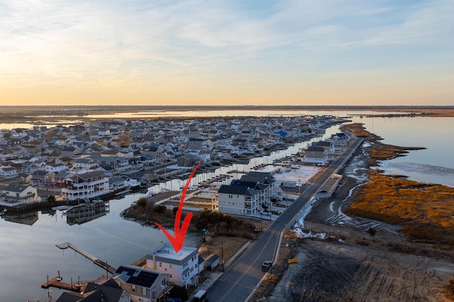 aerial view at dusk featuring a water view