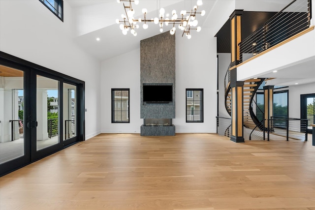 unfurnished living room featuring light hardwood / wood-style floors, french doors, a high ceiling, and a chandelier