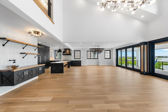 living room featuring an inviting chandelier, a towering ceiling, and light wood-type flooring