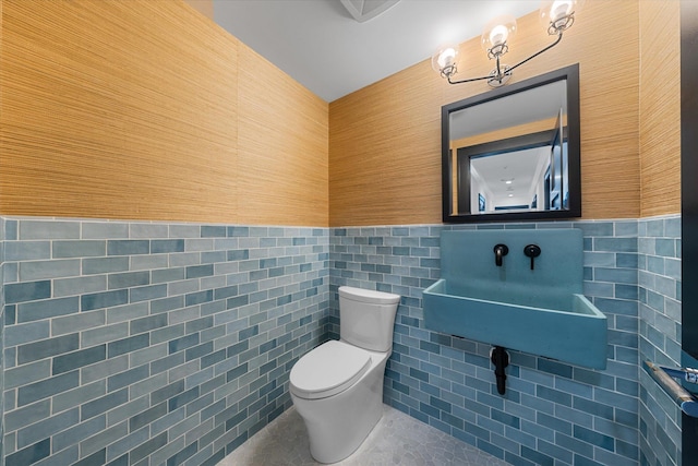 bathroom with tile patterned flooring, toilet, and tile walls