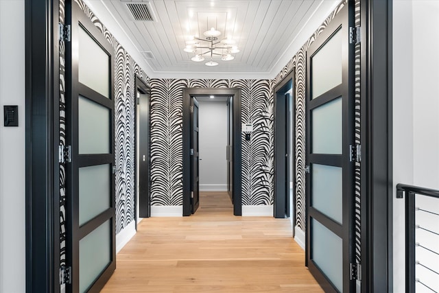 corridor with a notable chandelier, light hardwood / wood-style floors, and wood ceiling