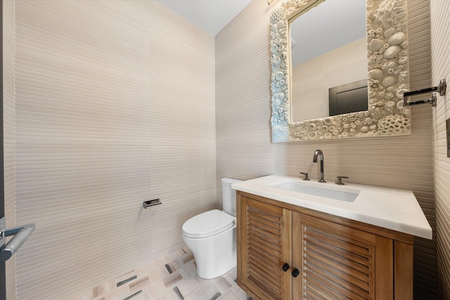 bathroom featuring vanity, toilet, and tile walls