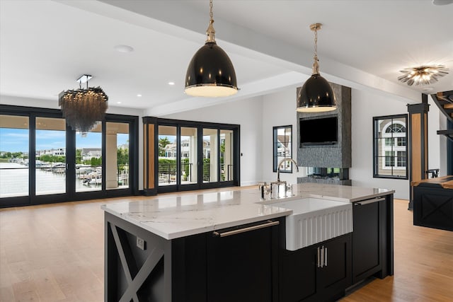 kitchen featuring french doors, a water view, sink, hanging light fixtures, and light wood-type flooring