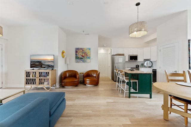 kitchen with open floor plan, appliances with stainless steel finishes, light wood-type flooring, and white cabinets