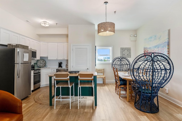 kitchen featuring light wood-style flooring, baseboards, white cabinets, light countertops, and appliances with stainless steel finishes