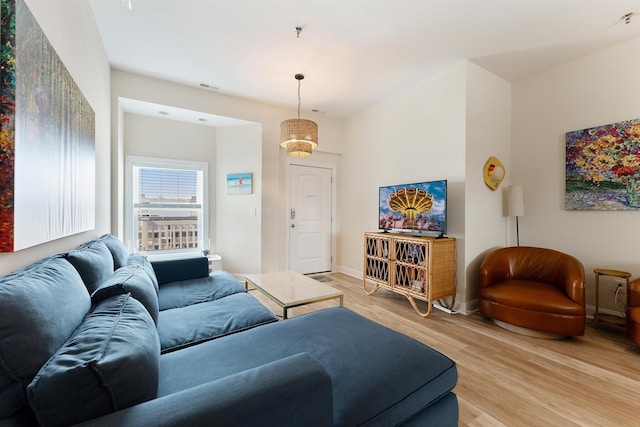 living room with light wood-style flooring, visible vents, and baseboards