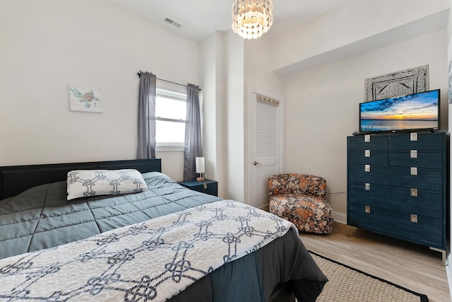 bedroom with baseboards, visible vents, an inviting chandelier, and wood finished floors