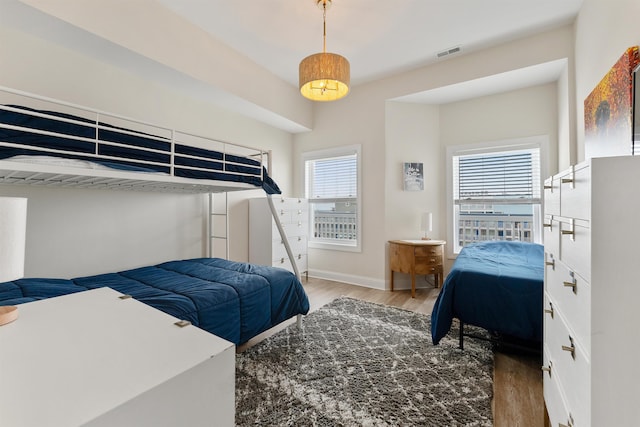 bedroom with baseboards, visible vents, and wood finished floors